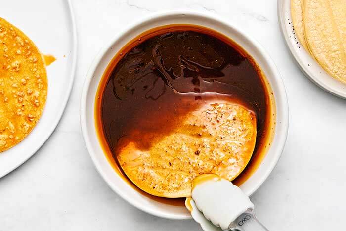 Dipping tortilla in birria consomme.