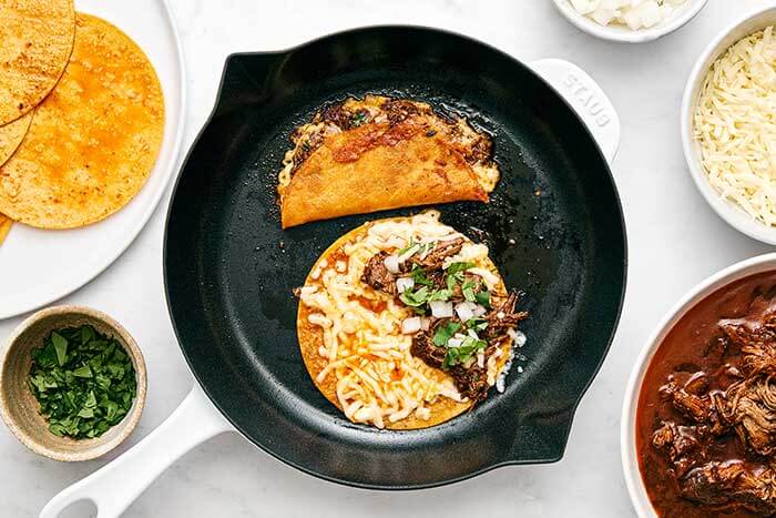 Making beef birria tacos in a pan.