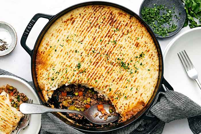 Scooping cottage pie with a spoon.