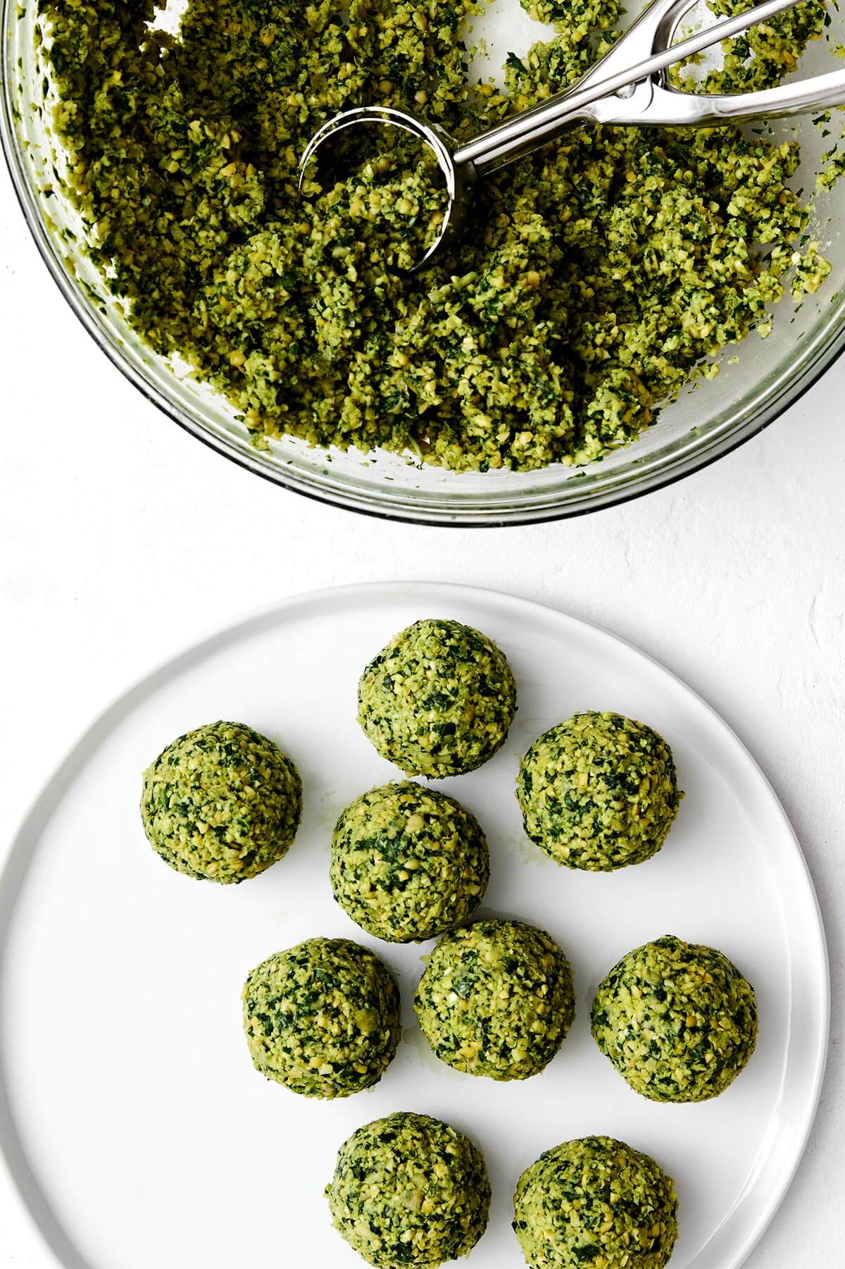 Falafel are delicious balls of chickpea and herb goodness in Middle Eastern cooking. They're naturally vegan and vegetarian, and great in wraps, pitas, sandwiches and salads. You can make fried falafel and baked falafel - I've got instructions for both! Forming falafel balls with a cookie scoop.