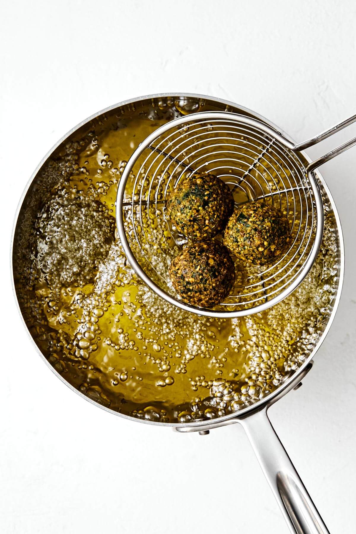 Falafel are delicious balls of chickpea and herb goodness in Middle Eastern cooking. They're naturally vegan and vegetarian, and great in wraps, pitas, sandwiches and salads. You can make fried falafel and baked falafel - I've got instructions for both! Deep frying falafels in a pot of oil.