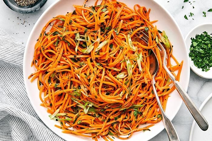A plate of carrot salad with a fork.