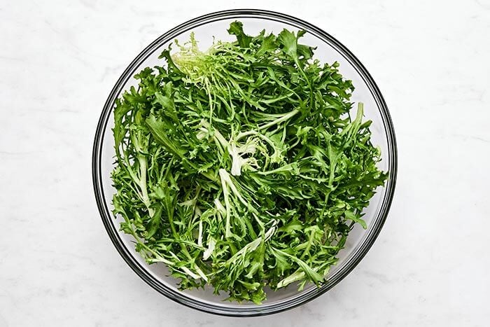 Prepping frisee lettuce in a bowl.