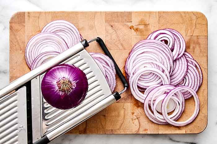 Slicing red onions with a mandoline.