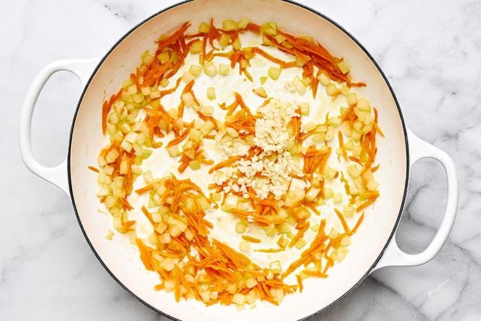 Cooked carrots and onion in a pan.