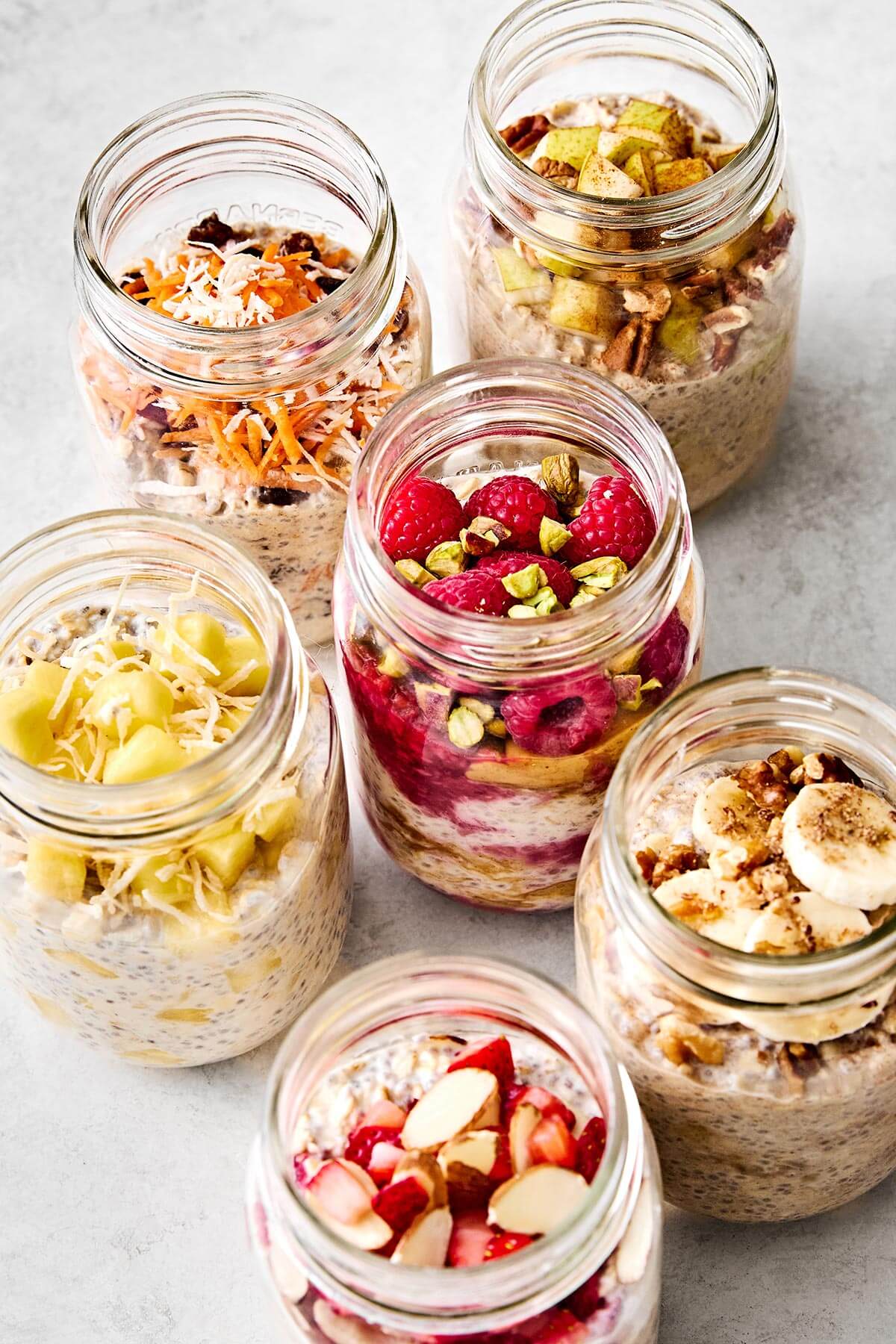 Learn how to make the perfect batch of overnight oats! This version is made with rolled oats, Greek yogurt, milk, chia seeds, and maple syrup for a deliciously ultra-creamy base. Plus, I'll show you how to make 6 different flavors using all the best fruits, including a strawberry protein flavor for an extra protein boost. Save this Downshiftology overnight oats recipe for inspiration when you're looking for an easy, healthy, no-cook breakfast meal prep. Overnight oats in many glass jars.
