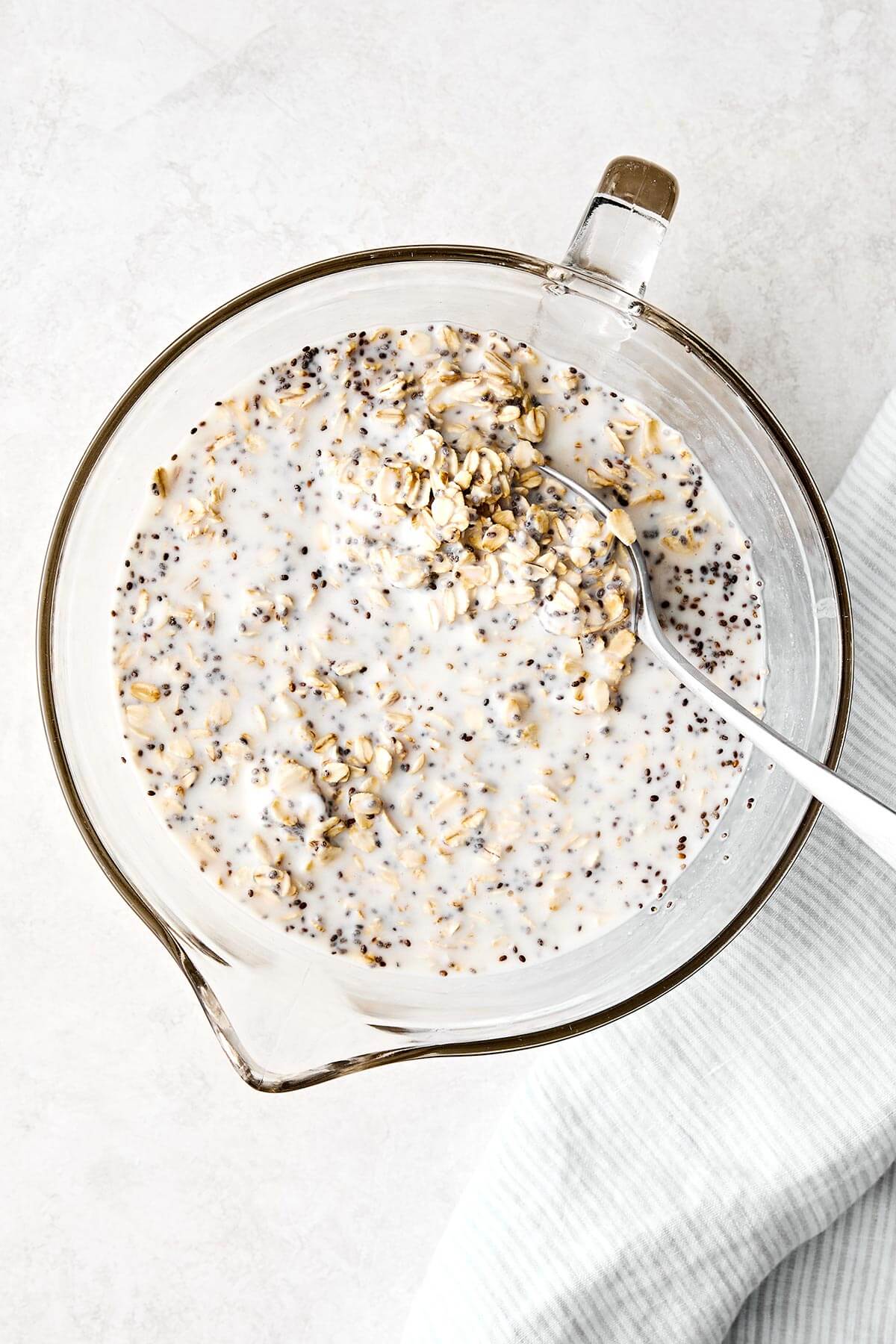 Learn how to make the perfect batch of overnight oats! This version is made with rolled oats, Greek yogurt, milk, chia seeds, and maple syrup for a deliciously ultra-creamy base. Plus, I'll show you how to make 6 different flavors using all the best fruits, including a strawberry protein flavor for an extra protein boost. Save this Downshiftology overnight oats recipe for inspiration when you're looking for an easy, healthy, no-cook breakfast meal prep. Overnight oats in a large bowl.