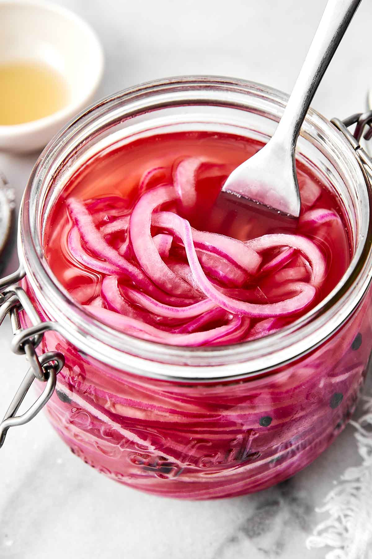 A jar of these pickled red onions is one of the easiest ways to instantly upgrade a meal! They’re tangy, slightly sweet, and extra punchy. A glass jar of quick pickled red onions.
