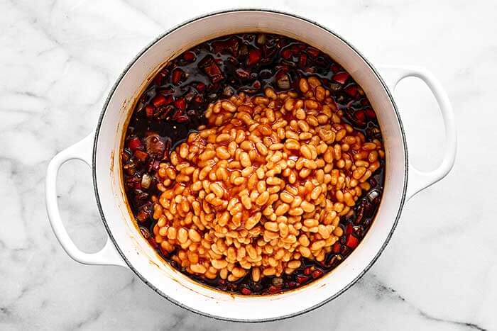 Adding baked beans into a pot.