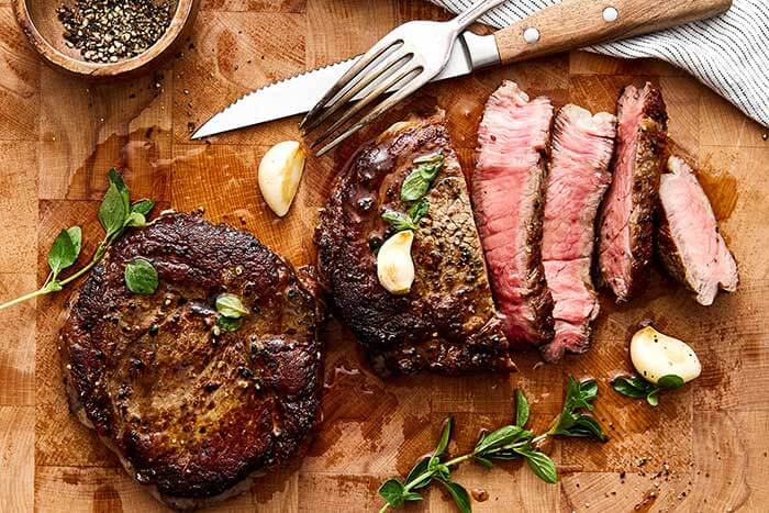 Wooden board with sliced ribeye steak.
