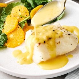 Drizzling orange beurre blanc on cod.