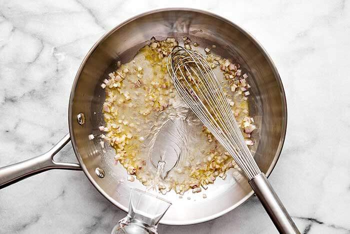 Cooking shallots and wine in a pan.