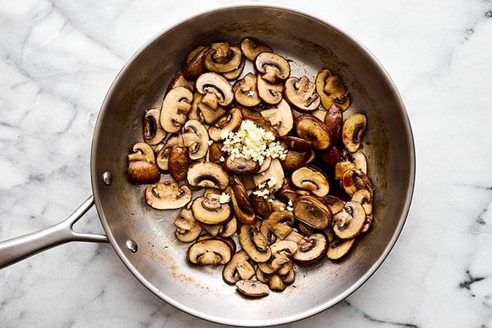 A pan with sauteed mushrooms and garlic.