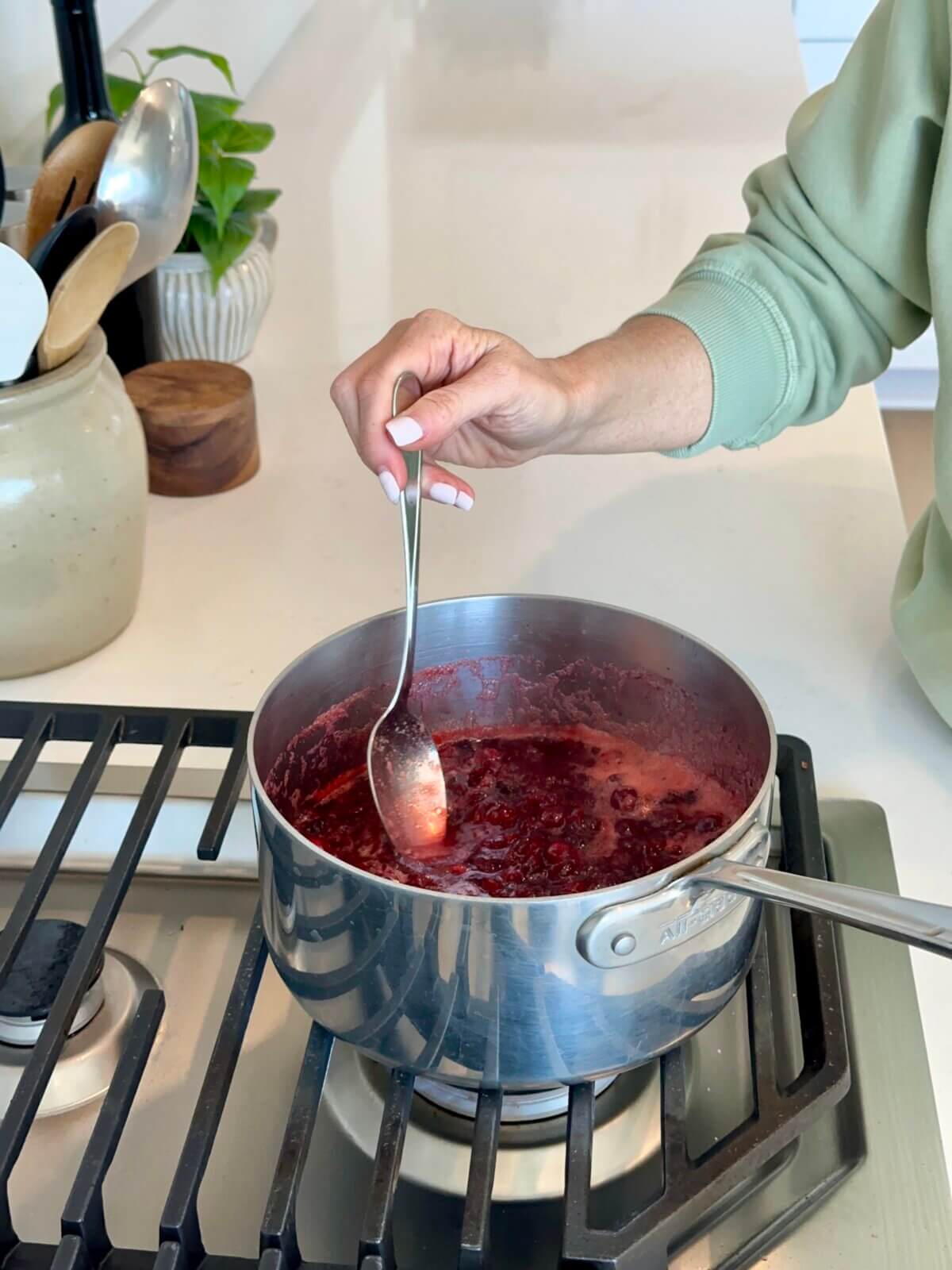 Lisa stirring the cranberry sauce in a pot on the stove.