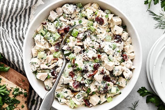 A bowl of turkey salad with a spoon.