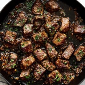 A cast iron skillet with garlic butter steak bites.