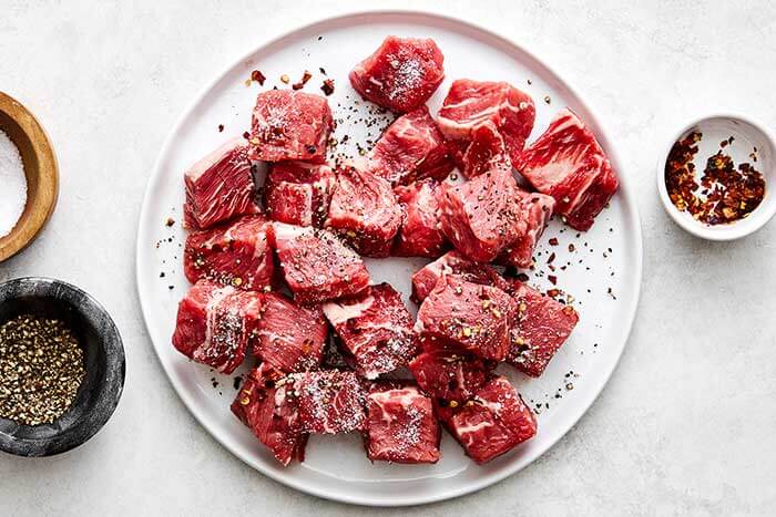 Seasoning steak pieces.