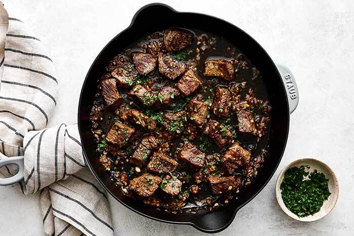Garlic butter steak bites in a cast iron pan.