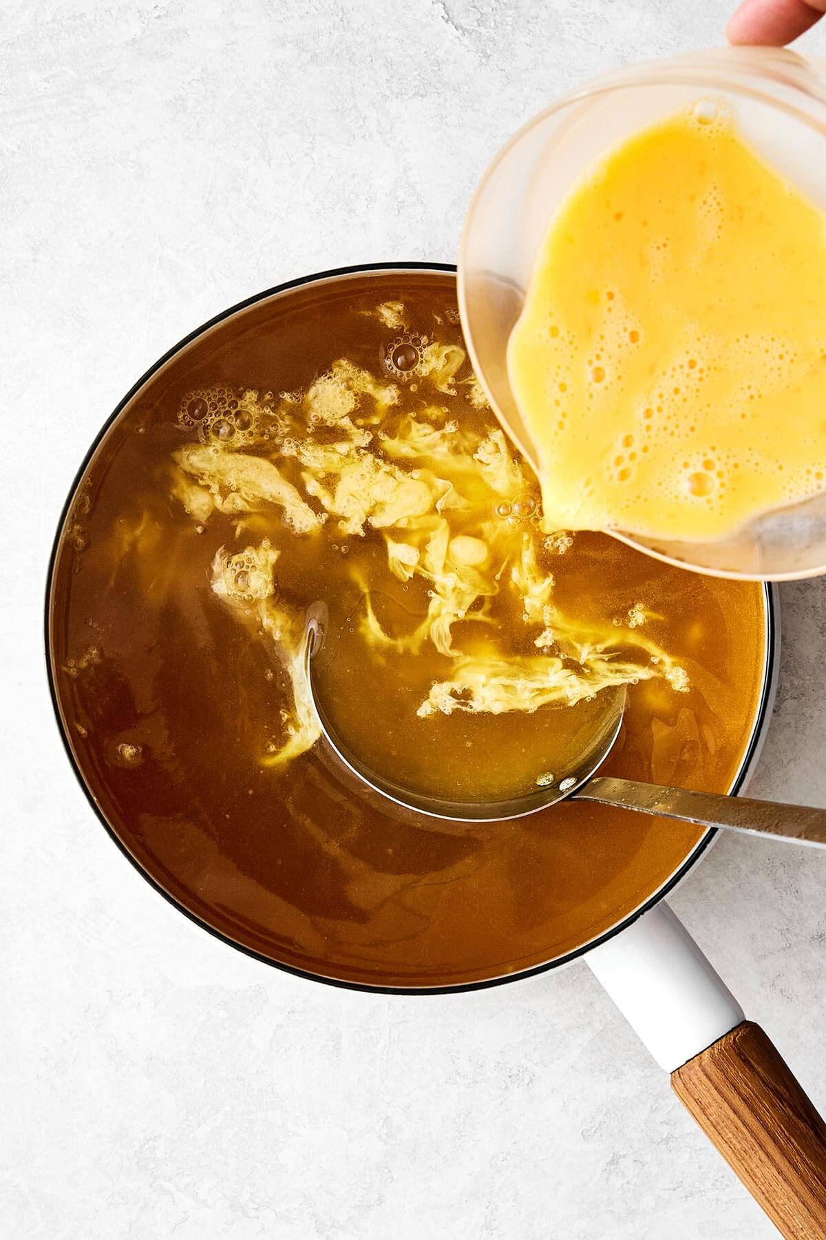 Swirling eggs into a pot of broth.