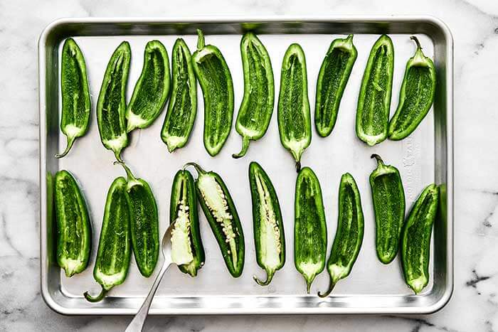 Prepping jalapeños on a sheet pan.