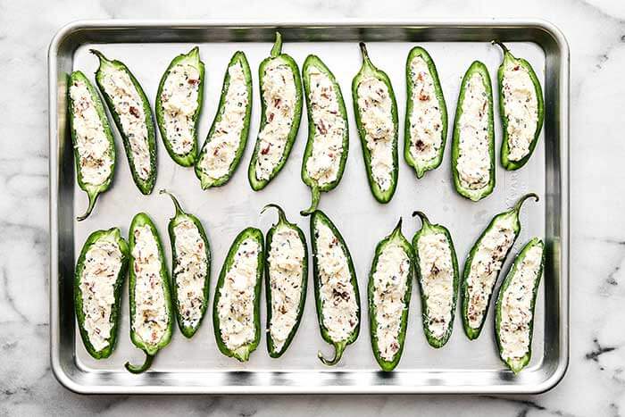 Prepped jalapeño poppers on a sheet pan.