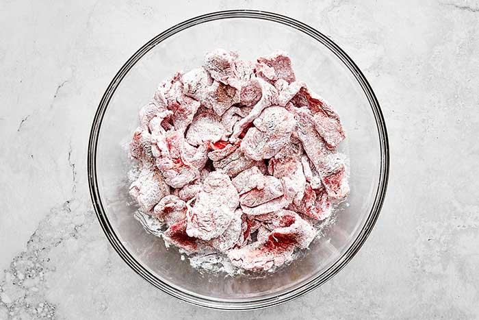 Cornstarch coated steak in a bowl.