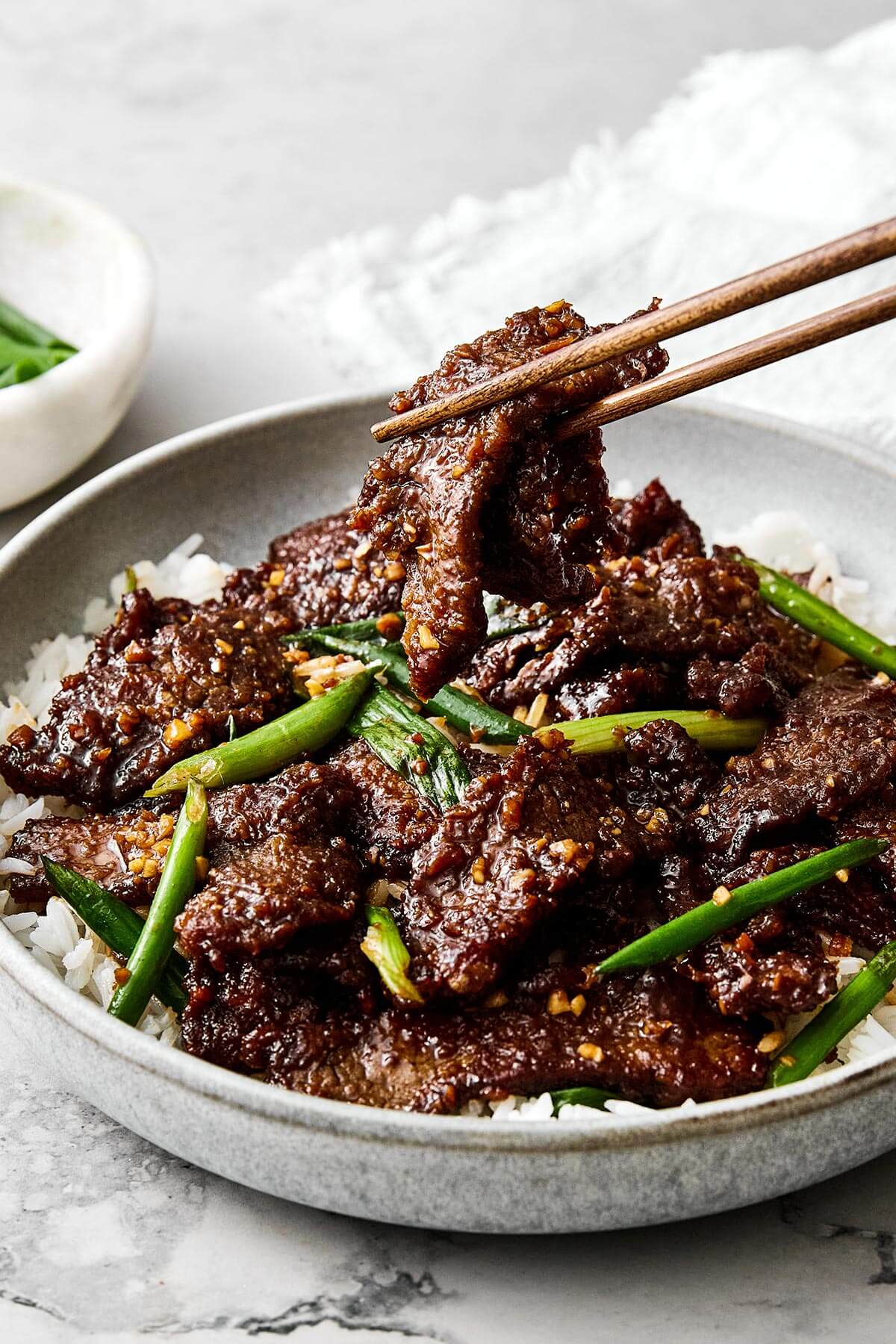 Picking up Mongolian beef with chopsticks.