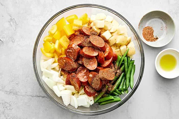 Tossing ingredients together for Cajun sheet pan.