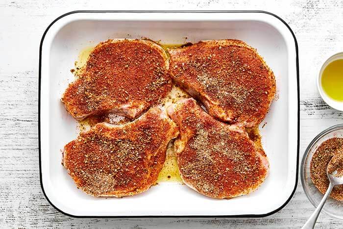 Seasoned pork chops in a baking dish.