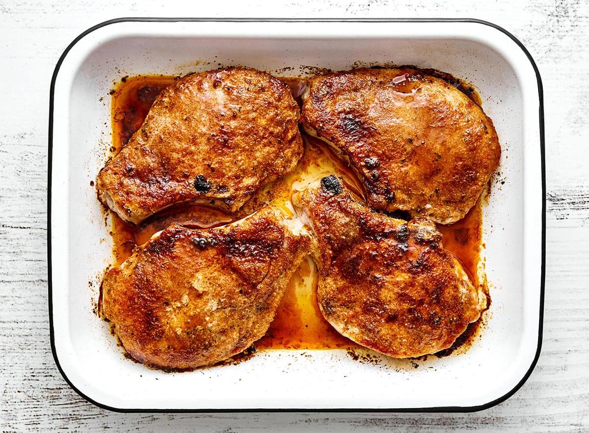 Baked pork chops in a whit baking dish.