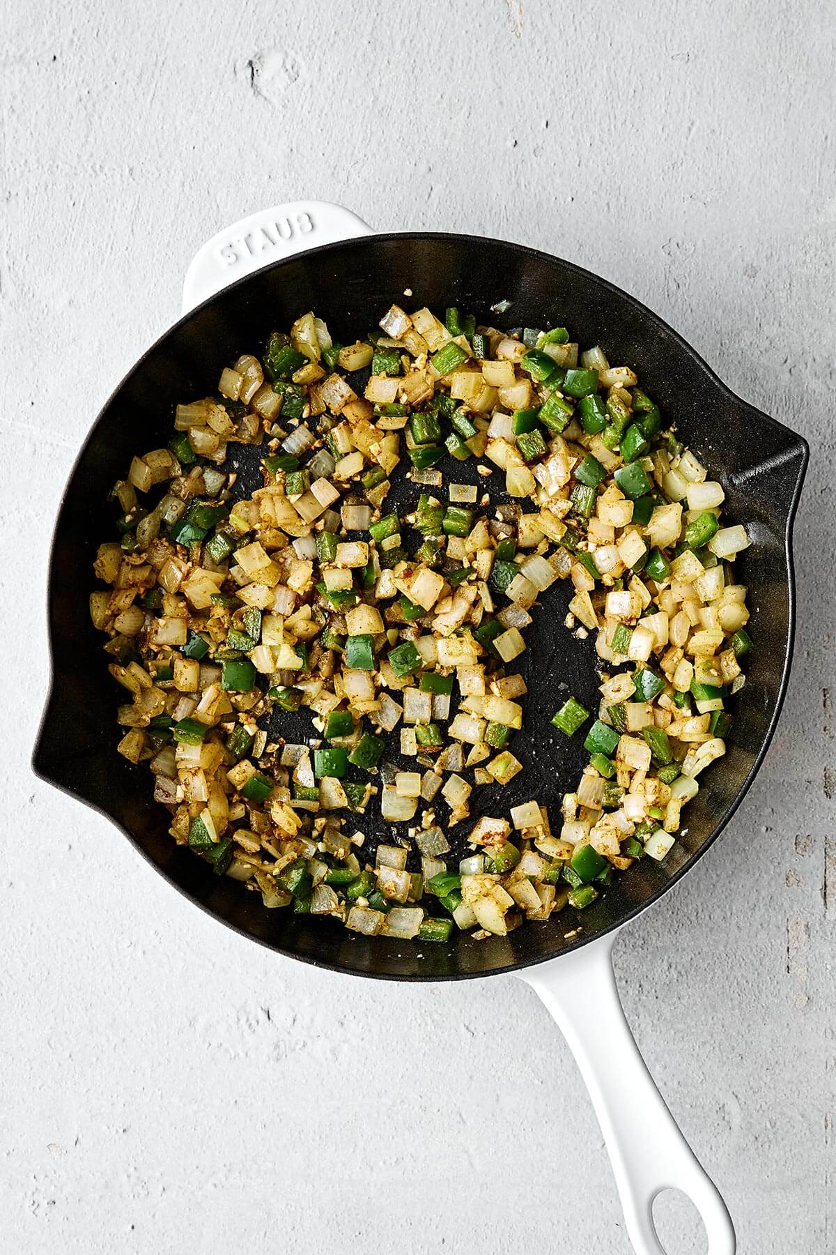 Sauteed onions and bell pepper in a pan.