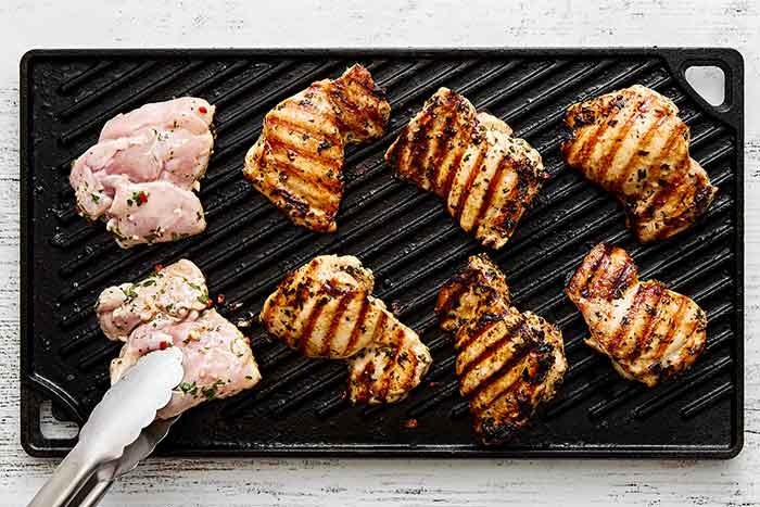 Grilling chicken thighs on a grill pan.
