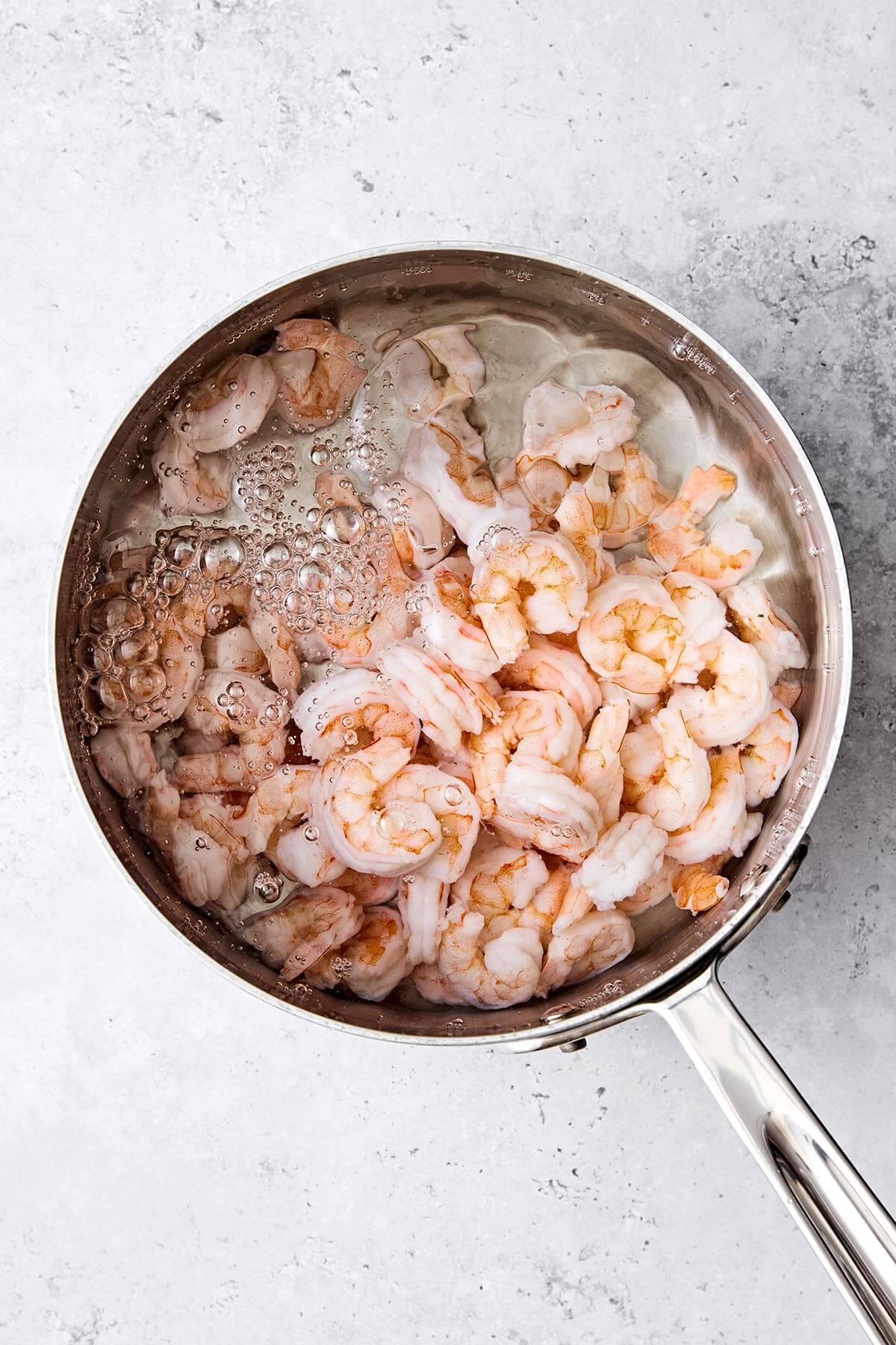 This mango avocado shrimp salad is sweet, crunchy, and tossed in a fresh honey lime dressing. It's the ultimate refreshing summer salad! Cooking shrimp in a pot.