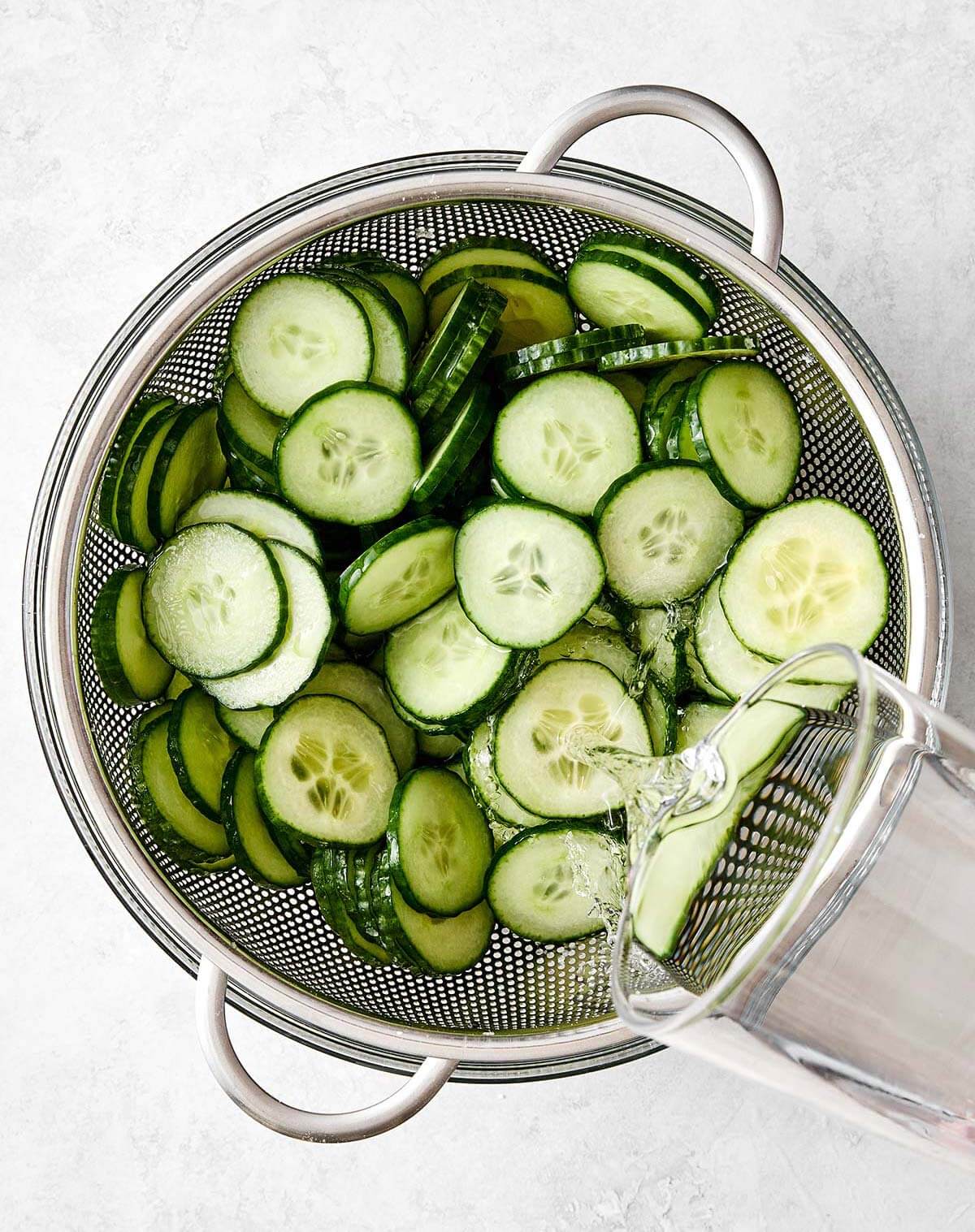 Rinsing cucumber slices in a colander.