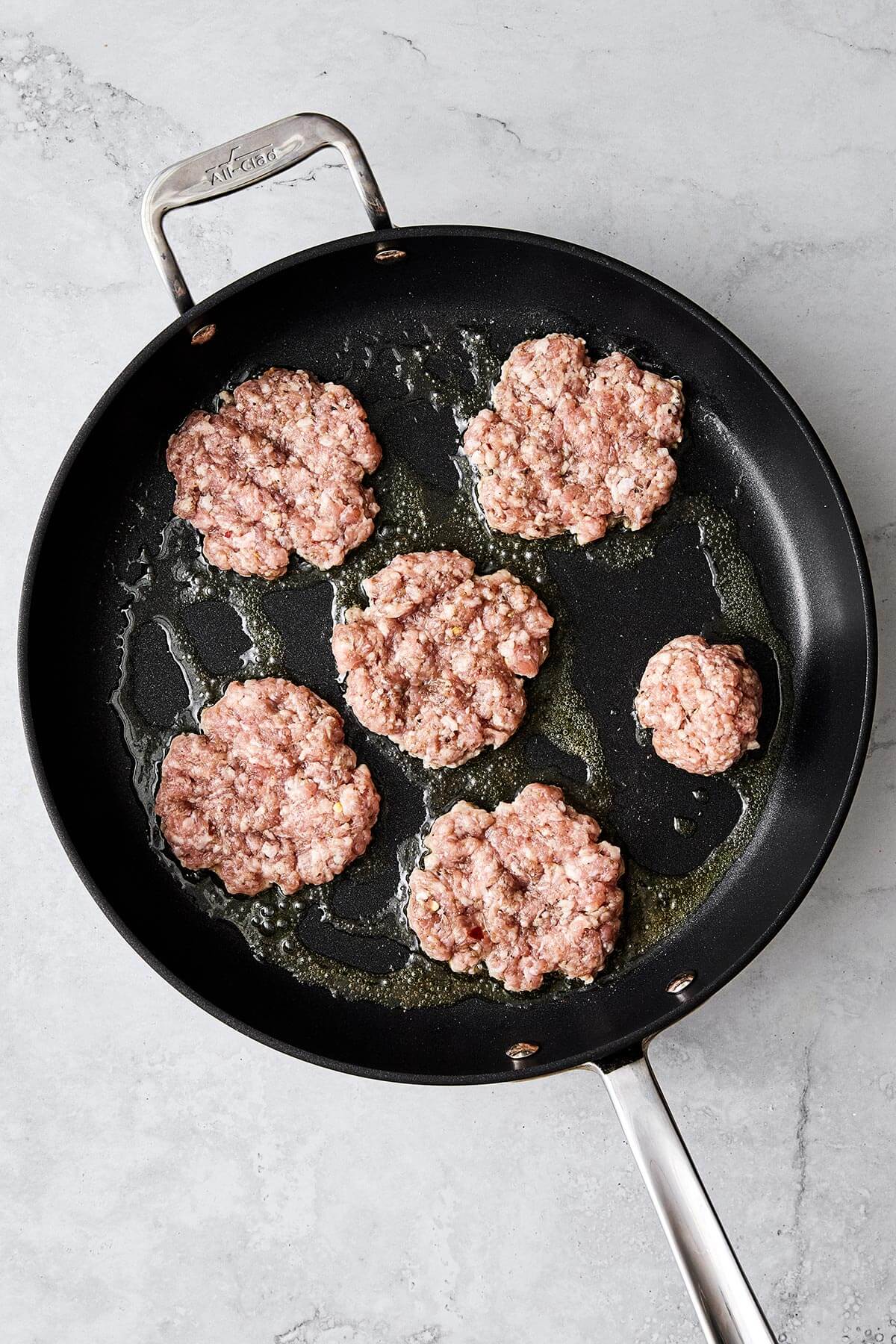 Cooking breakfast sausages in pan.
