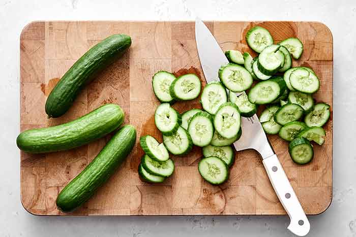 Chopping cucumbers on a board.