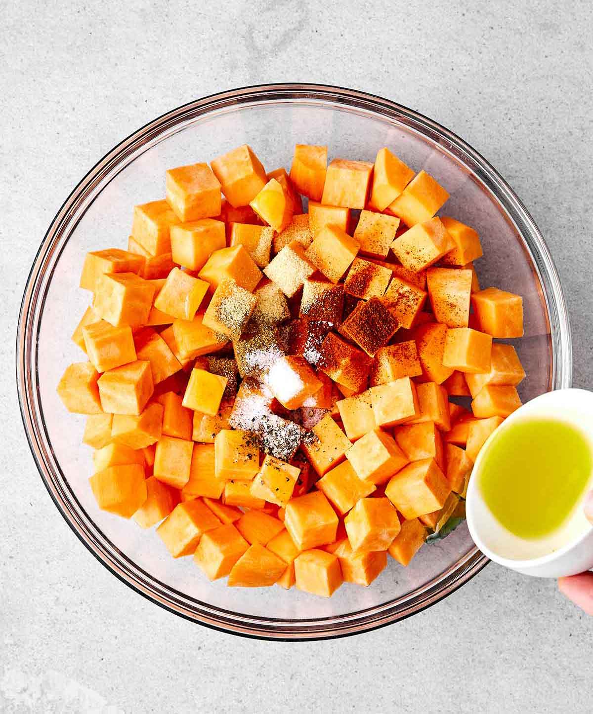 Step one of making a sweet potato salad: toss the potatoes in seasoning.