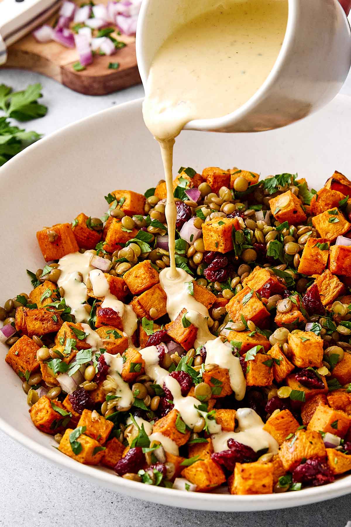 Drizzling maple tahini dressing on a sweet potato salad.