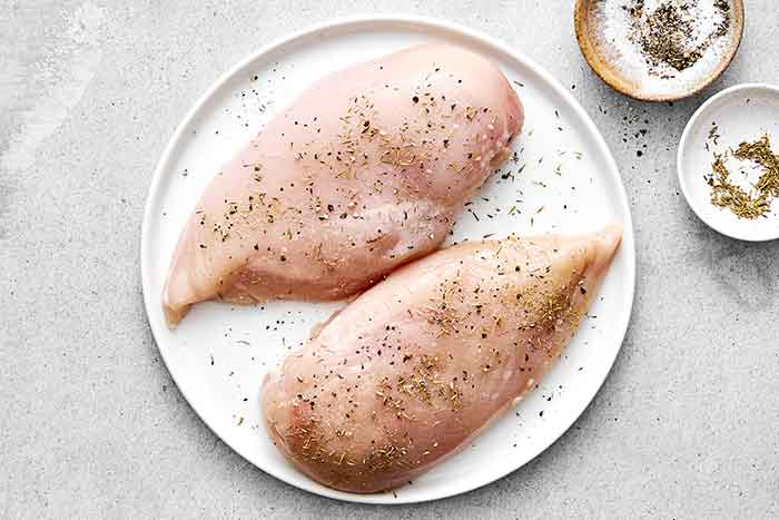 Seasoning chicken breasts.