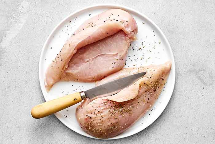 Slicing chicken breasts open for stuffed chicken.