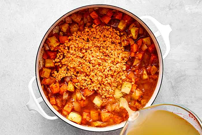 Step three of red lentil soup: add broth and lentils.