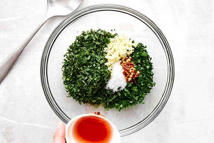 Step two of mint chimichurri: add ingredients to a bowl.