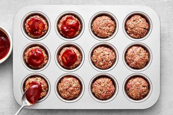 Step three of meatloaf muffins: add sauce.