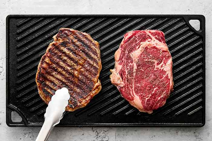 Grilling ribeye steaks on a grill pan.
