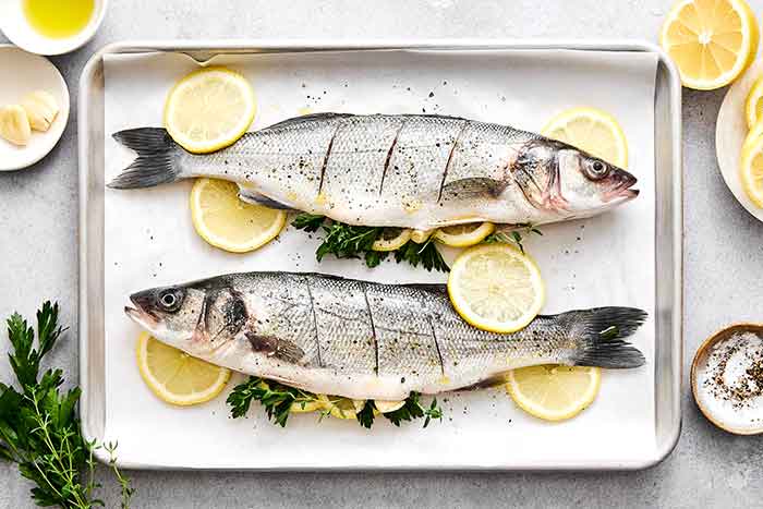 Seasoning whole branzinos before roasting.