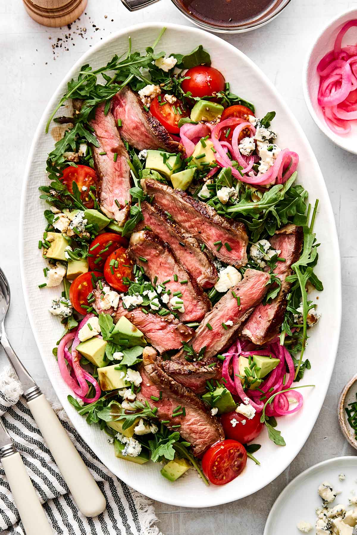 This steak salad piled high with grilled steak, arugula, fresh veggies, and a balsamic dressing is my favorite summer salad yet! The best summer steak salad on a plate.
